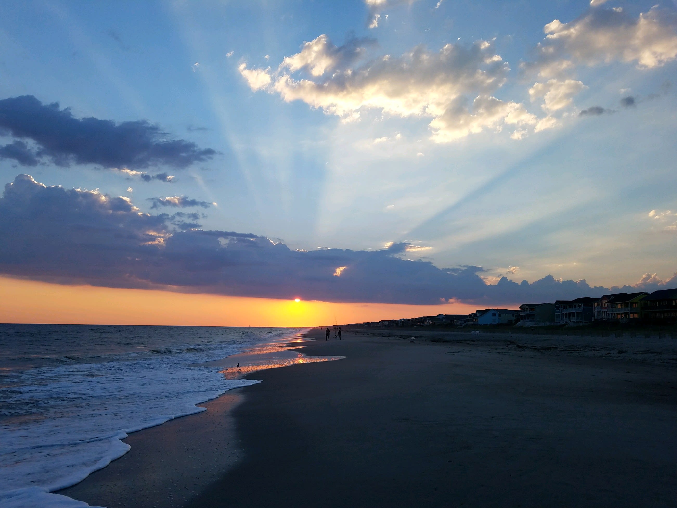 Sun peaking through the clouds at sunset on Holden Beach