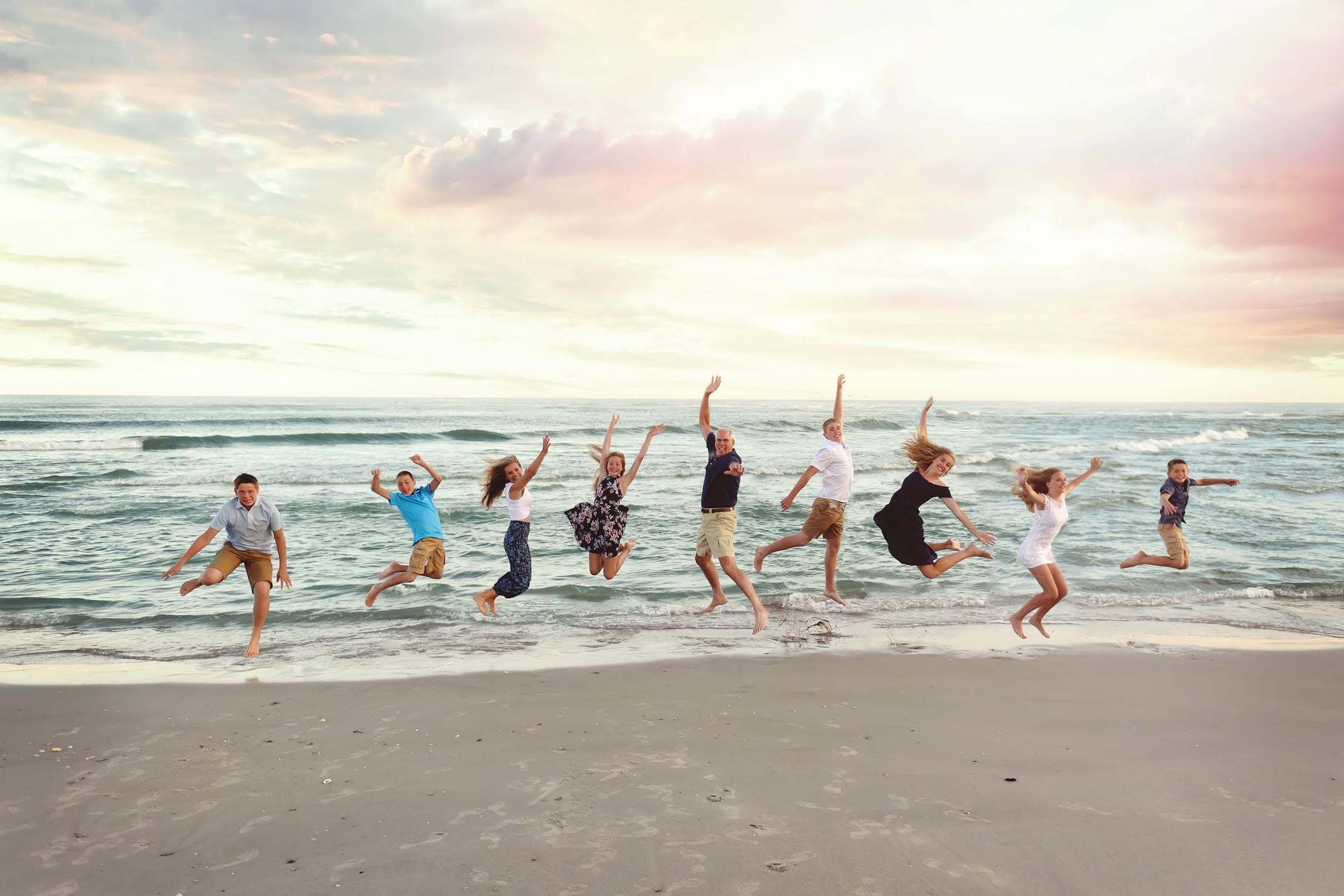 family jumping at holden beach