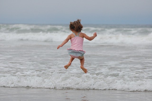 girl jumping waves on the beach